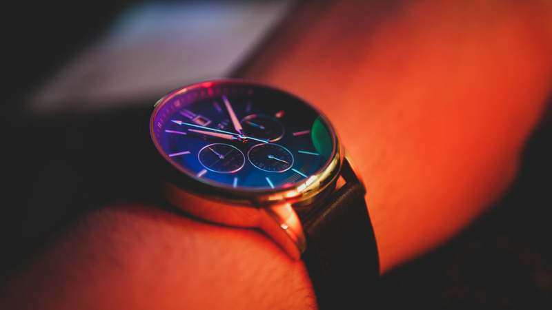 Close-up of five iconic watches showing distinct dial colors: navy blue, matte black, olive green, champagne, and deep burgundy